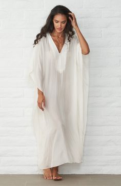 Eco friendly caftans and tunics inspired by the ocean, made on main street. Ethically sourced and locally made in Los Angeles. This effortless caftan is perfect for everyone.   The deep v-neckline is framed by a long placket for a flattering decolletage.   The elegant, feather-weight silk feels like a dream on the skin and floats effortlessly over the body.  In this milky shade of white, it is sheer, so it is perfect as a cover up.   Or, pair it with a slip and wear it as a dress.  In 100% washable silk, this one is as easy as it gets.  No belt, no worries.  It works on every body, every time.   Sheerness: very Model height: 5'9" Fabric: 100% Silk CDC What is Silk CDC? Check out our fabric glossary for the breakdown. Hand wash and hang to dry or dry clean. Kaftan Designs, Kaftan Style, Half Slip, Mode Casual, Caftan Dress, Spring Fashion Trends, White Silk, Bohemian Dress, Outfits Casuales