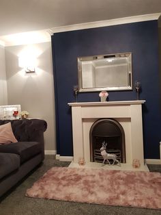 a living room with a couch, fireplace and mirror on the wall next to it