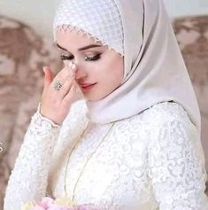 a woman wearing a white hijab and holding a bouquet of flowers in her hand