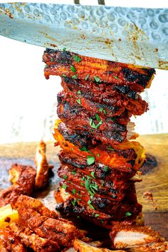 a large stack of food sitting on top of a wooden table next to a knife