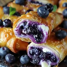 blueberry pastry rolls are stacked on top of each other with fresh blueberries in the middle