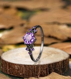 a purple ring sitting on top of a tree stump with leaves around it and in the background