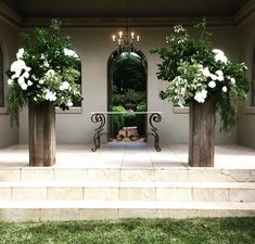 three vases with white flowers are on the front steps of a house that has stairs leading up to it