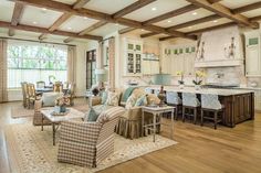 a living room filled with furniture and lots of wood flooring next to a kitchen