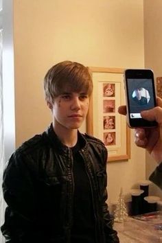 a man holding up a smart phone in front of his face while standing next to another person