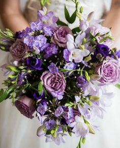 a bride holding a bouquet of purple flowers