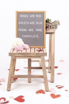 two wooden chairs with flowers on them and a sign that says roses are red violets are blue