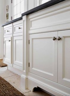 a kitchen with white cabinets and brown rugs on the floor in front of it