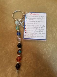 a keychain with a bible verse and charms attached to it on a table