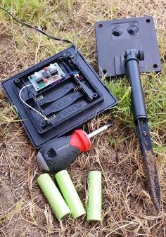 an electronic device laying on the ground next to some batteries and other items in it