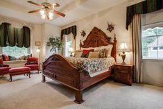 a bedroom with a large bed and two red chairs in front of the window,