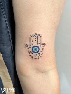 a hamsa tattoo with an evil eye on the side of the arm is shown