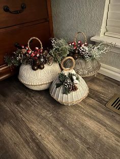 two white baskets with pine cones and berries on them