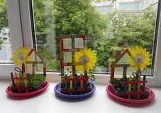 three small houses with sunflowers in them on a window sill next to a potted plant