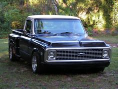 an old black pickup truck parked in the grass