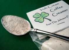 a scoop of coffee creamer next to a packet of powdered sugar on a green tablecloth