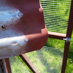 a close up view of the side of a bird feeder with grass in the background