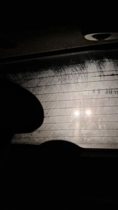 the back window of a car at night with two lights shining on it's side