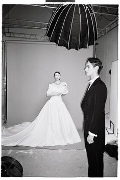 a woman in a white dress standing next to a man in a suit