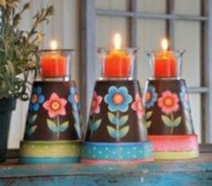 three vases with candles in them sitting on a table next to a potted plant