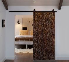 an open door leading to a bedroom with a bed in the background and lights hanging from the ceiling