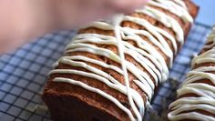 a loaf of bread with white icing on it sitting on top of a cooling rack