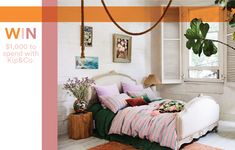 a white bed sitting under a window next to a green plant in a living room