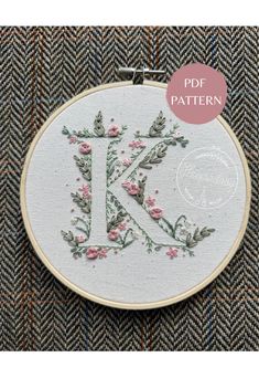 the letter k is made up of flowers and leaves on a white background with a pink circle