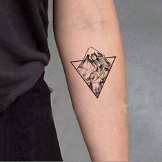 a man's arm with a mountain and triangle tattoo on the left inner forearm