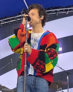 a man standing on top of a stage holding a microphone in front of his face