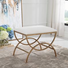 a white bench sitting on top of a rug in front of a painting and flowers