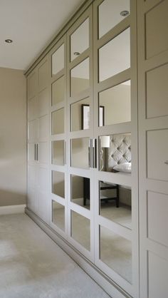 an empty room with mirrored doors and white furniture