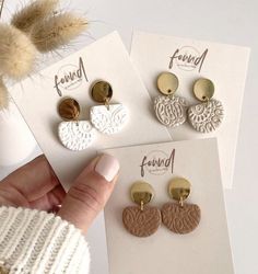 three pairs of earrings are shown in front of a white card with the word friend written on it