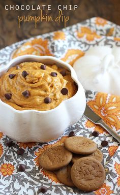 chocolate chip pumpkin dip in a white bowl with cookies on the table next to it