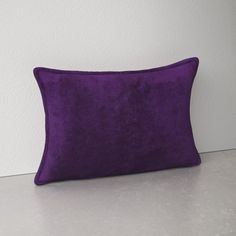 a purple pillow sitting on top of a white counter next to a wall and floor