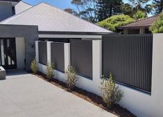 a white house with black fence and bushes