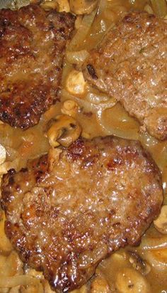 two meat patties with mushrooms and onions in a skillet, ready to be eaten