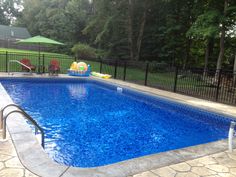 an empty swimming pool in a backyard with a slide and water play area on the other side