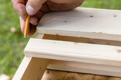 a person is holding a pencil and writing on a piece of wood that has been made into a bench