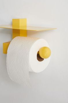 a yellow and white toilet paper holder on the wall