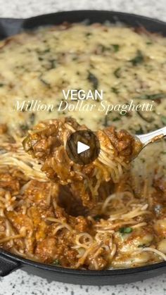 a skillet filled with spaghetti and meat being stirred by a ladle to make it