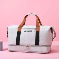 a white duffle bag sitting on top of a pink table next to a small box