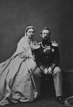 an old black and white photo of a man and woman sitting next to each other