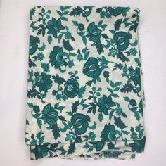 a green and white floral pattern on a piece of cloth with blue flowers in the center