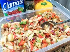 a plastic container filled with pasta salad next to a can of clamado juice