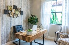 a desk with a laptop on it next to a chair and potted plant in front of a window