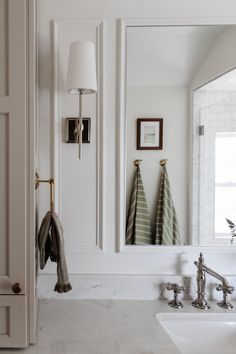 a bathroom with two sinks and towels hanging on the wall next to it's mirror