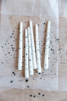 four white candles sitting on top of a piece of wax paper next to black dots