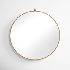 a round mirror hanging on the wall with a gold chain attached to it's side