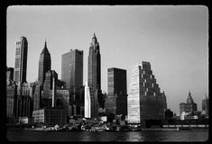 black and white photograph of new york city from across the water with skyscrapers in the background